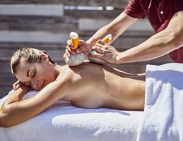Massage aux tampons pratiqué sur une dame allongée sur le ventre. 