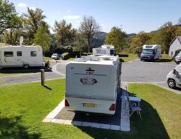 Wohnmobile auf einem Campingplatz in Liefrange, Luxemburg, umgeben von Bäumen und Hügeln.